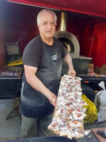 Joe holding a long board of Nutella and strawberry dessert pizzas fresh from the oven