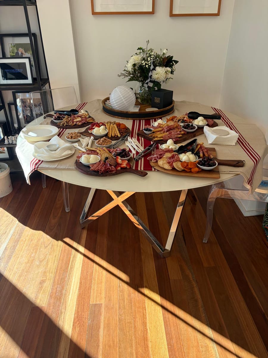 A grazing table of cured meats, cheeses, olives and fruit set out with plates stacked ready