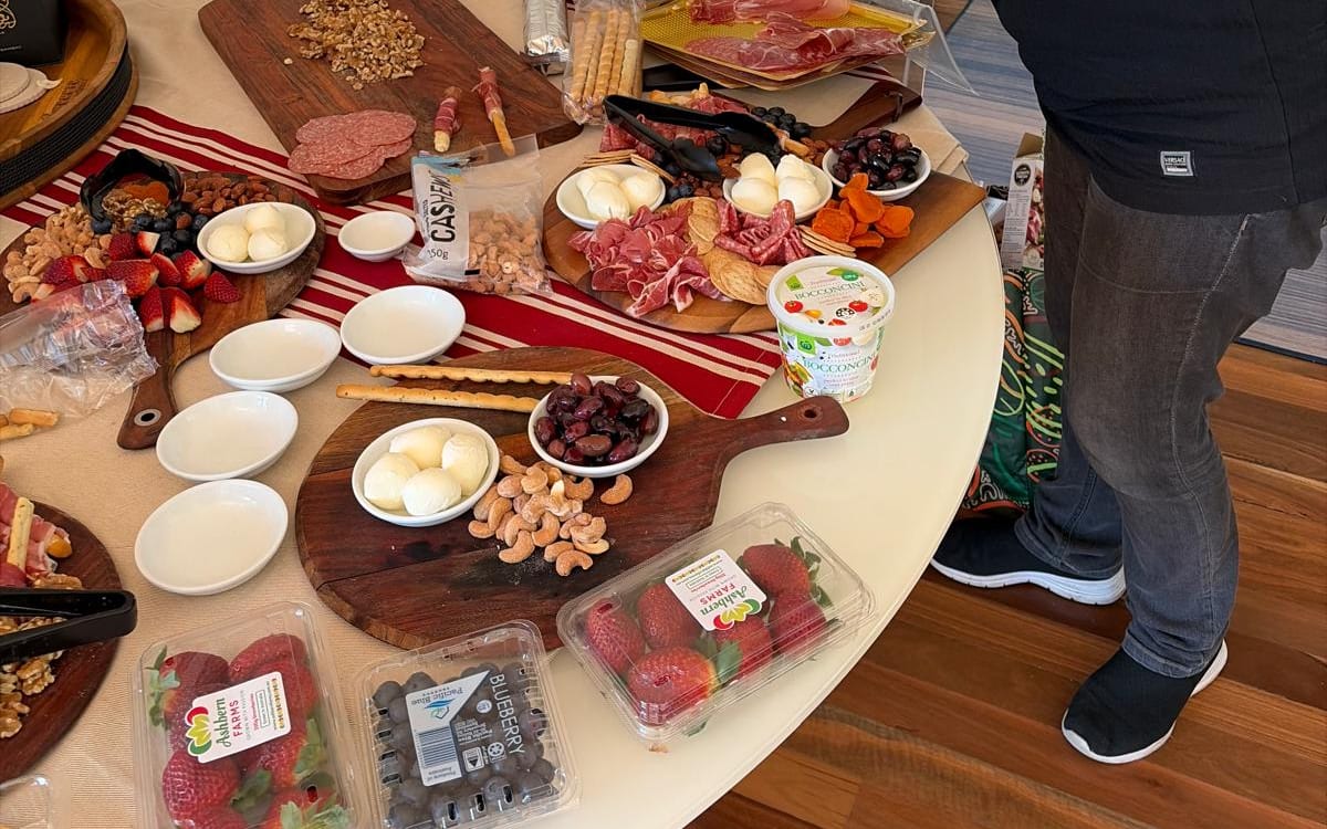Grazing boards of cured meats, bocconcini, nuts and strawberries being set out for a party at home